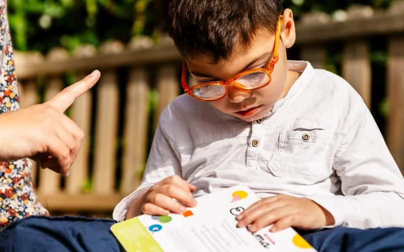 Young boy reading a book wearing glasses