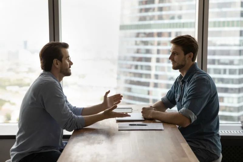 Two people discussing documents across a table