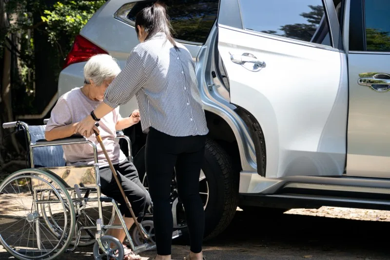 Person assisting a wheelchair user into a car