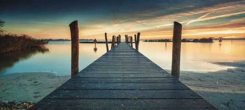 Wooden dock extending into calm lake at sunrise
