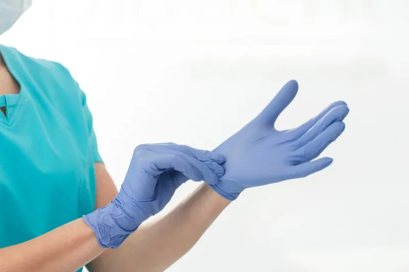 Person putting on blue nitrile glove