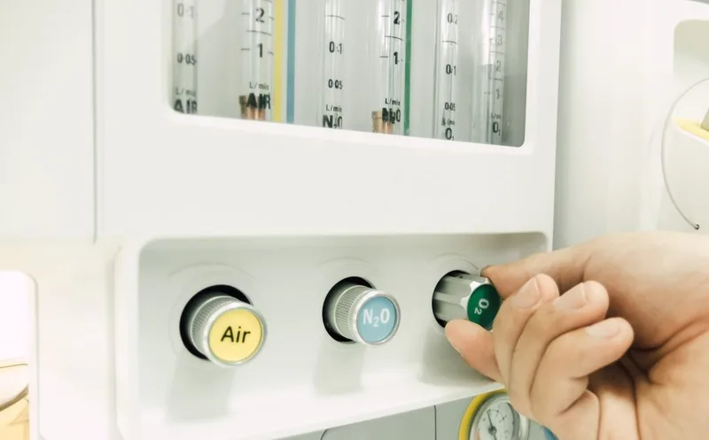 Hand adjusting nitrous oxide control on medical panel