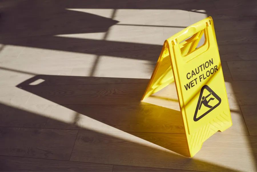 Yellow caution wet floor sign on wooden floor