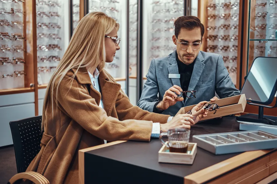 Customer trying on eyeglasses with salesperson