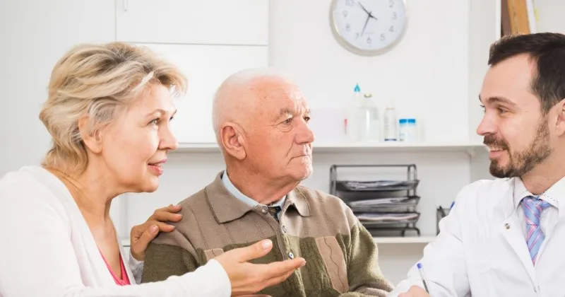 Elderly man talking with doctor and companion