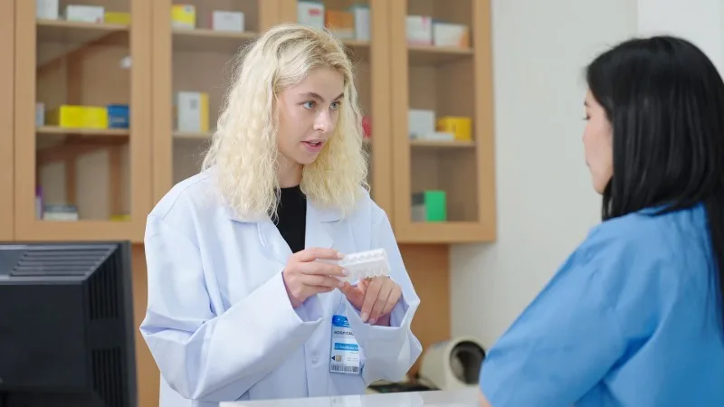 Pharmacist speaking with customer at counter