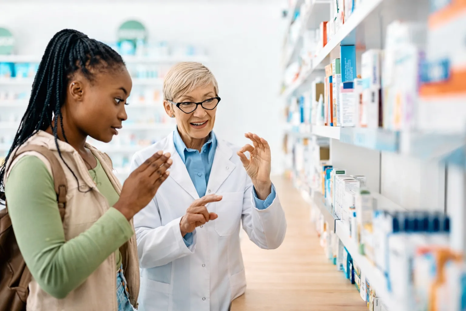 Pharmacist using BSL with customer in aisle