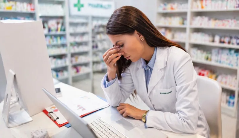 Pharmacist at counter rubbing eyes