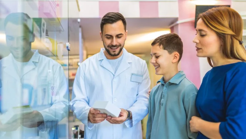 Pharmacist speaking with woman and young boy