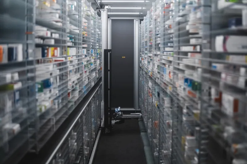 Narrow aisle between automated pharmacy shelving