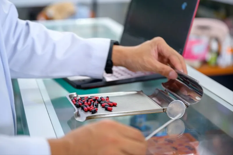 Hands pouring red and black capsules onto tray