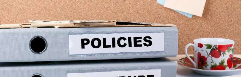 Stacked office binders labeled POLICIES