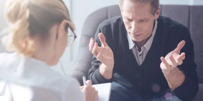 Middle-aged man speaking with female professional