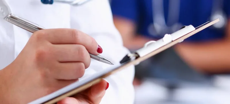 Person writing on medical clipboard
