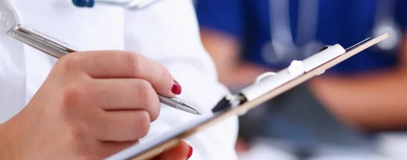 Close-up hands writing on a clipboard