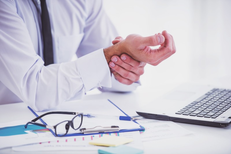 Person holding their wrist at a desk