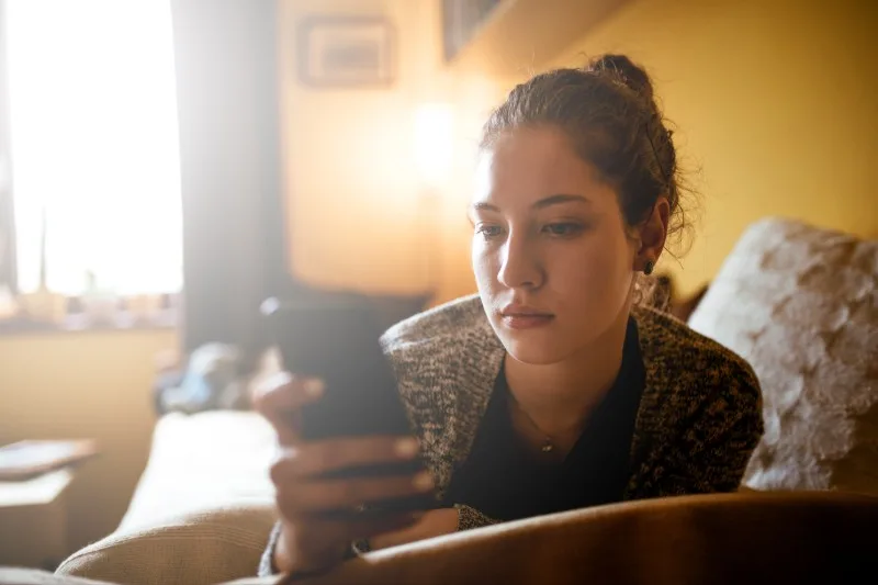 Teenager sitting on couch looking at smartphone