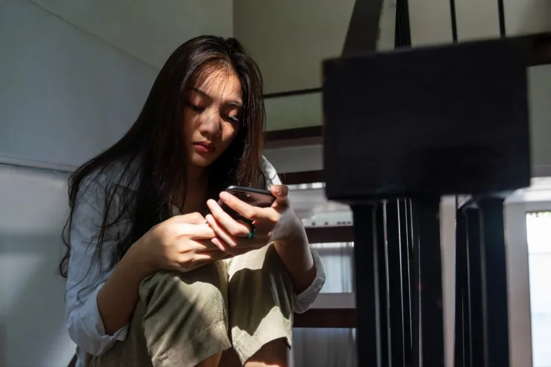 Teenager sitting indoors looking at a smartphone