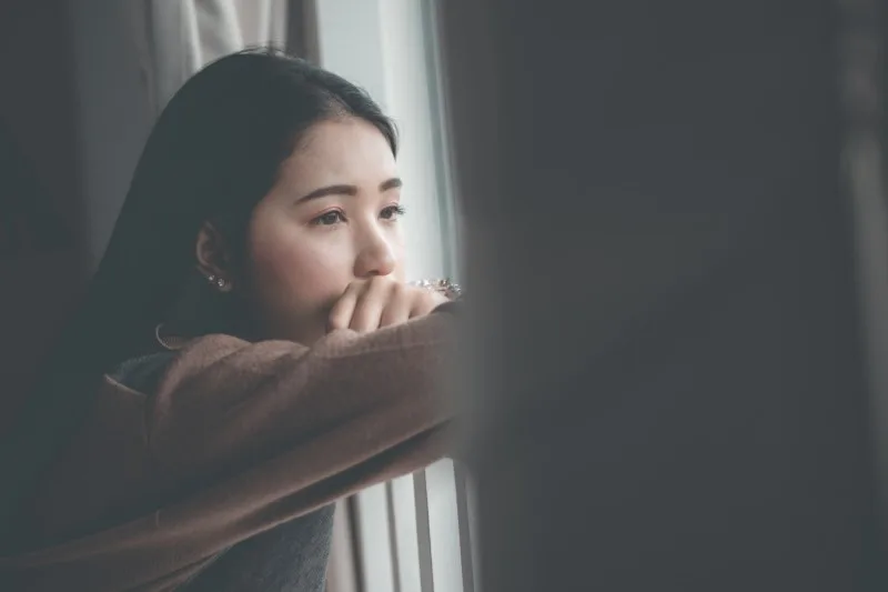Young person looking out window thoughtfully