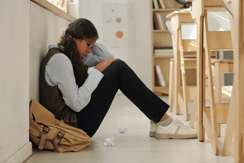 Teen sitting on floor hugging knees