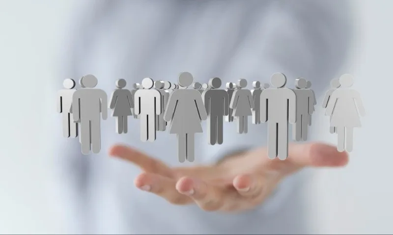 Floating paper cutout people above open hand