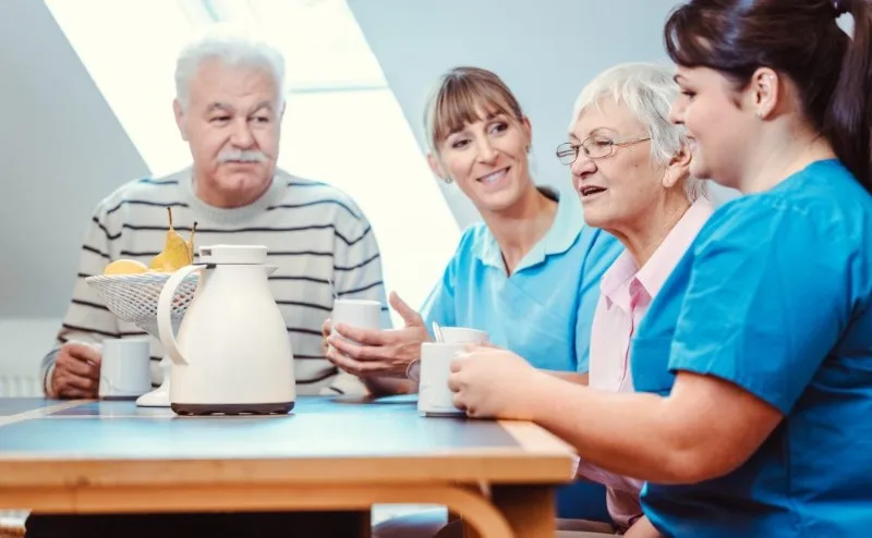 Two care workers talking with two older adults at a table