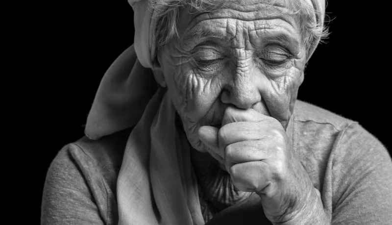 Elderly person with hand to mouth in black and white