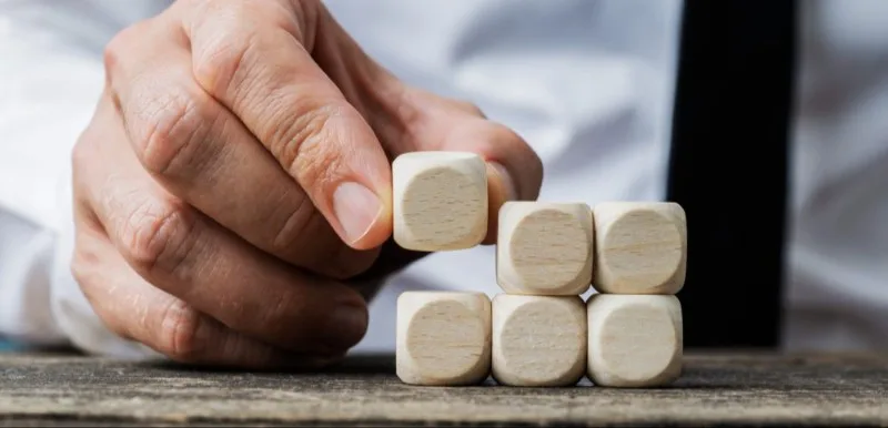 Hand stacking wooden blocks on table