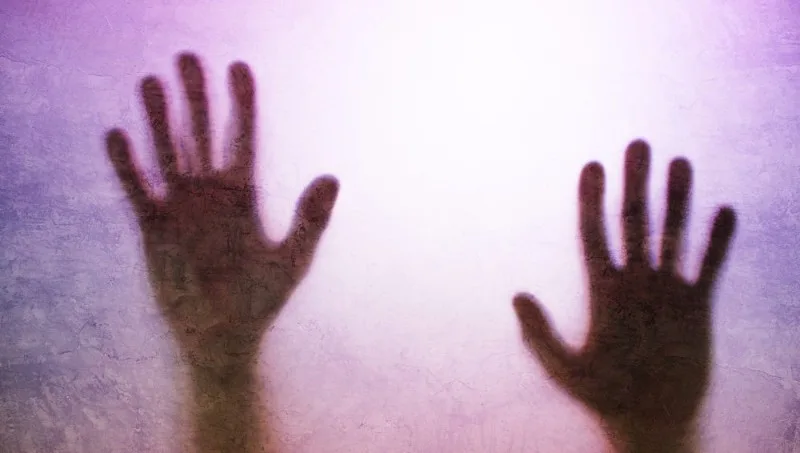Two hands pressed against frosted surface