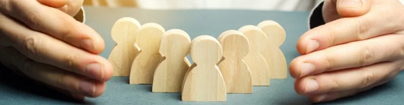 Hands surrounding wooden people figures