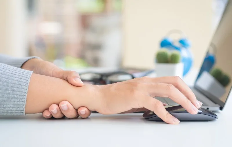 Person holding their wrist while using a computer mouse