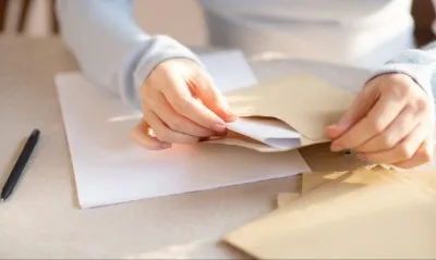 Hands putting paper into a brown envelope