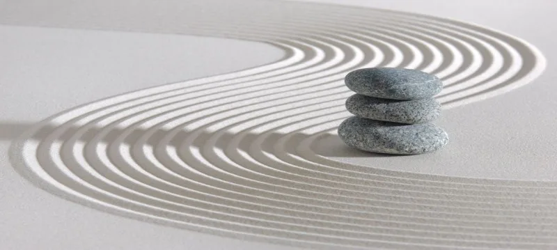 Three stacked gray stones on raked sand