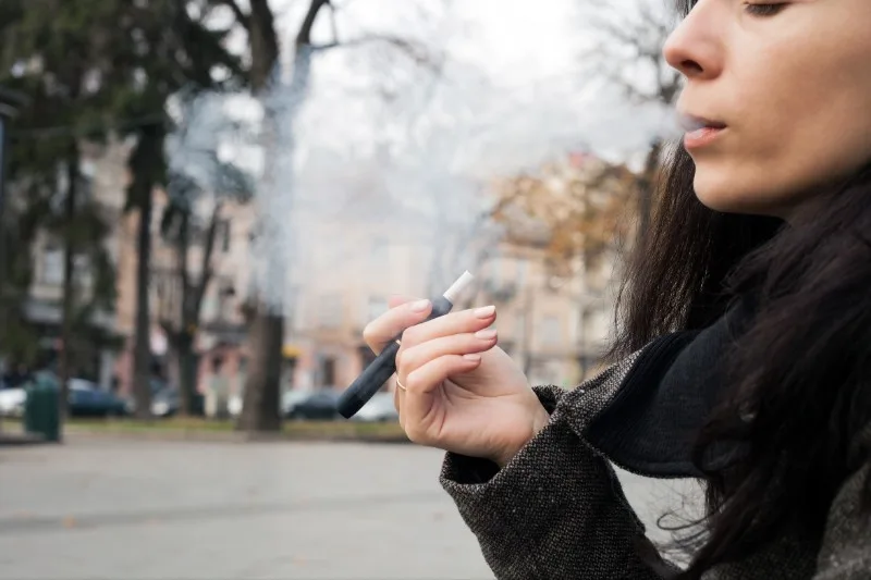 Teenage person exhaling vapor outdoors