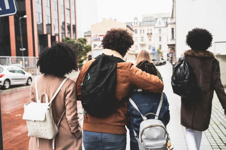 Four teenagers walking together down a city sidewalk