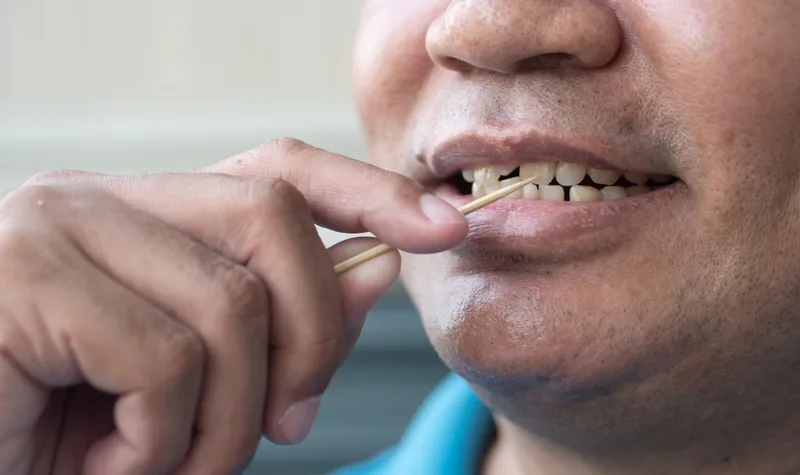 Person using wooden toothpick between teeth