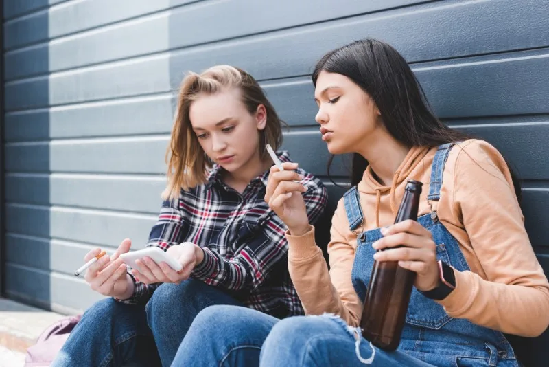 Two young people sitting drinking and smoking