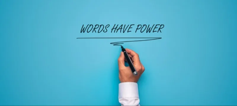 Hand underlining phrase 'WORDS HAVE POWER' on blue background